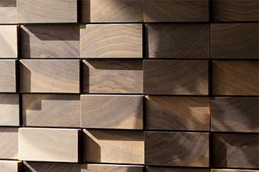 Puinen seinäpaneeli, jossa on suorakulmaisia paloja ja varjoja, luoden kolmiulotteisen vaikutelman.