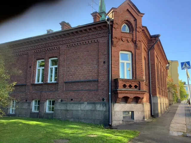 Kaksikerroksinen tiilirakennus ja sen kivijalka.